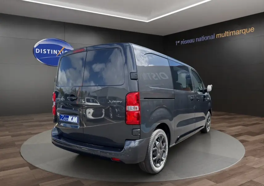 Vue 3/4 arrière droite d'un Citroën Jumpy gris foncé avec vitres arrière opaques et jantes noires.