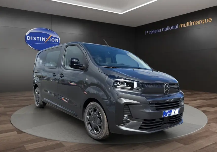 Vue 3/4 avant droit d'un Citroën Jumpy gris foncé avec calandre noire et jantes sombres en showroom.