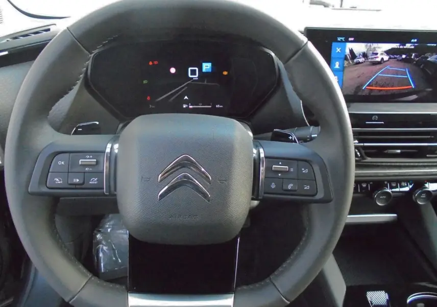 Volant cuir du Citroën C5 X 2022 avec commandes intégrées et écran affichant la caméra de recul en arrière-plan.