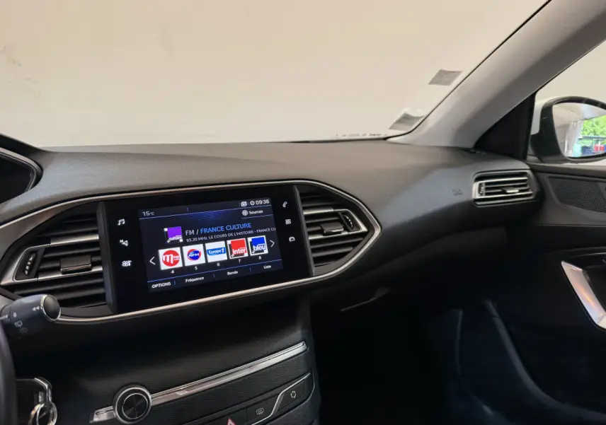 Intérieur de la Peugeot 308 2021 vue côté passager, tableau de bord noir avec écran tactile multimédia allumé.