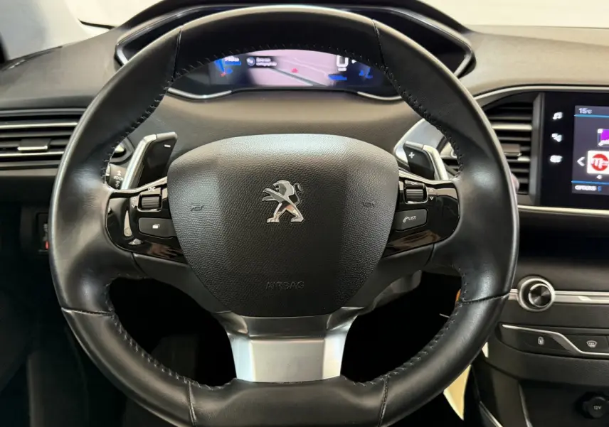 Gros plan sur le volant cuir noir du Peugeot 308 2021 avec tableau de bord numérique et écran tactile visible à droite.