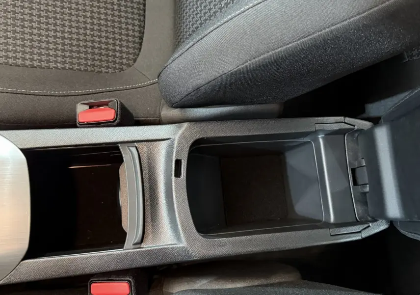 Vue plongeante sur la console centrale noire et les sièges tissu gris foncé de la Peugeot 308 blanche de 2021