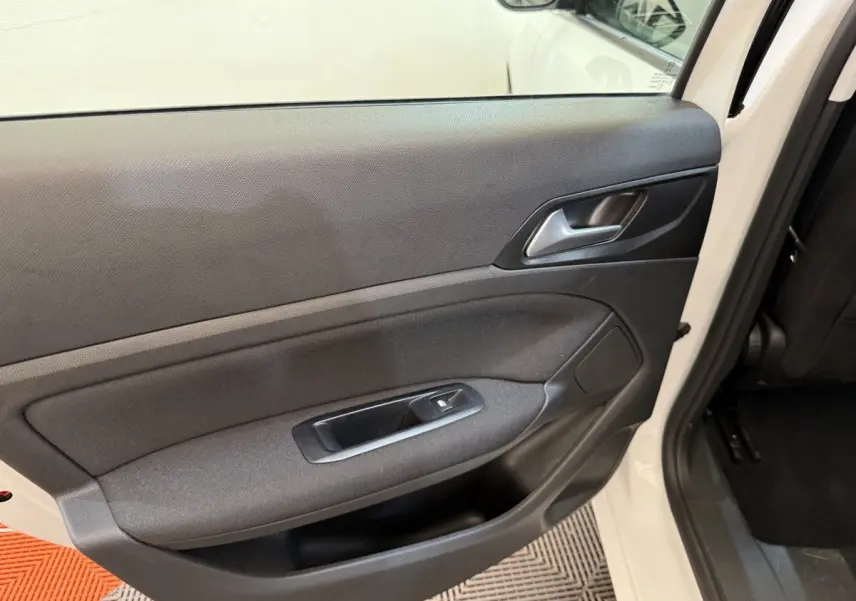 Vue intérieure de la porte arrière gauche d'une Peugeot 308 blanche, avec panneau noir et commande de vitre électrique.