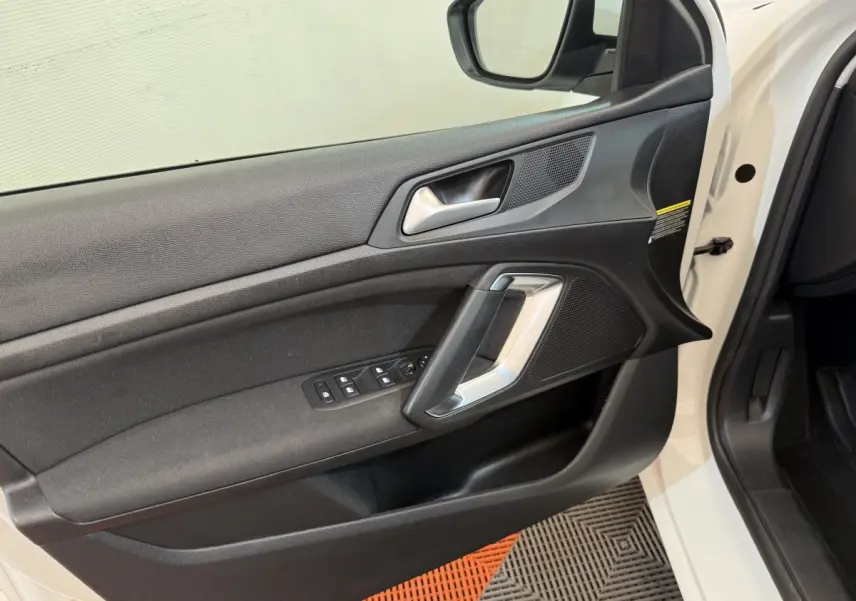 Vue intérieure de la porte avant gauche noire avec poignée argentée et commandes des vitres d'une Peugeot 308 blanche 2021