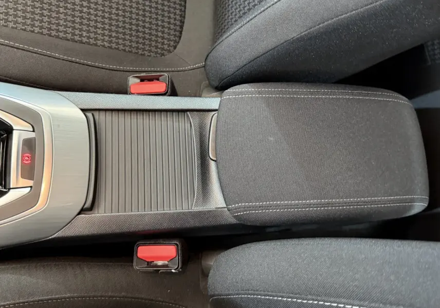 Vue rapprochée de la console centrale noire et des sièges tissu gris foncé de la Peugeot 308 blanche de 2021.