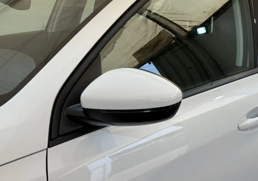 Gros plan sur le rétroviseur droit blanc d'une Peugeot 308 BlueHDi 130 2021, avec la portière visible en arrière-plan.