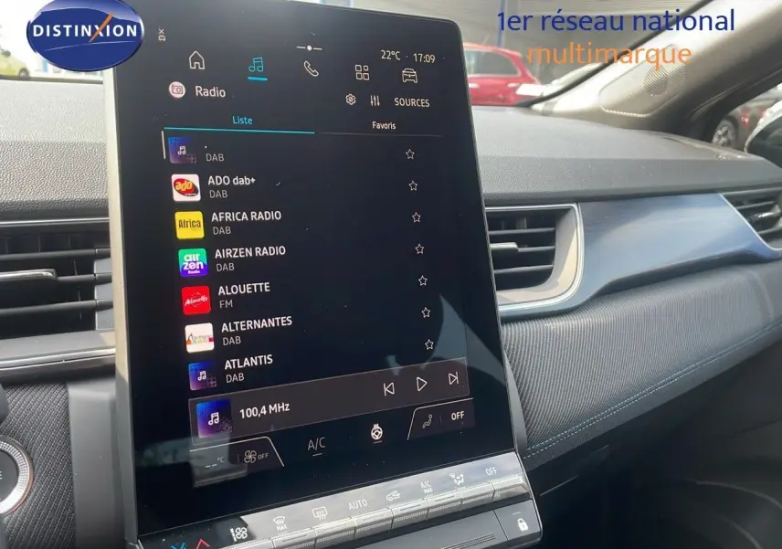 Écran tactile central affichant les stations radio dans l'habitacle du Renault Captur gris cassiopée toit noir, vue de côté droit.
