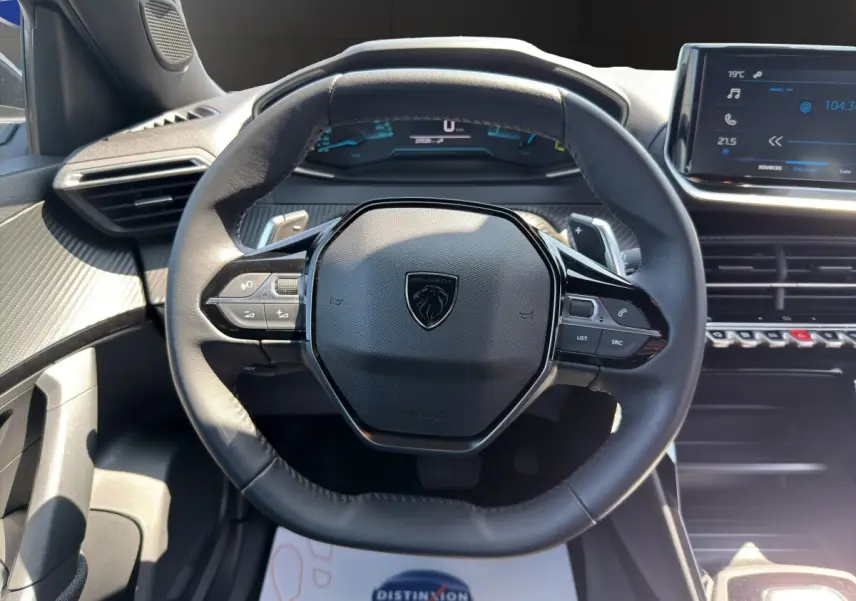 Vue rapprochée du volant cuir multifonctions noir du Peugeot 2008 Hybrid 145 e-DCS6 Style avec tableau de bord digital.