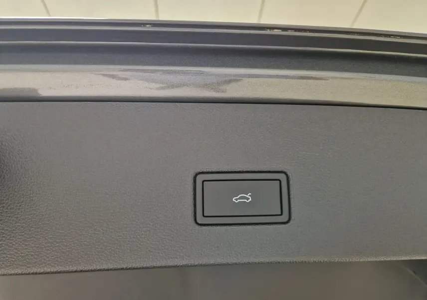 Bouton de commande d'ouverture du coffre sur la garniture intérieure d'un Volkswagen T-Roc gris Indium Metal 2025.