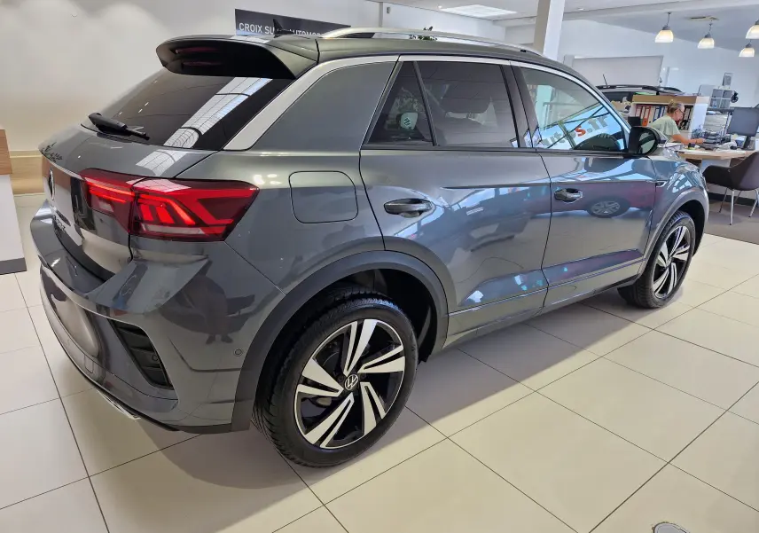 Vue 3/4 arrière droite d'un Volkswagen T-Roc gris Indium Metal avec jantes alliage bicolores en showroom.