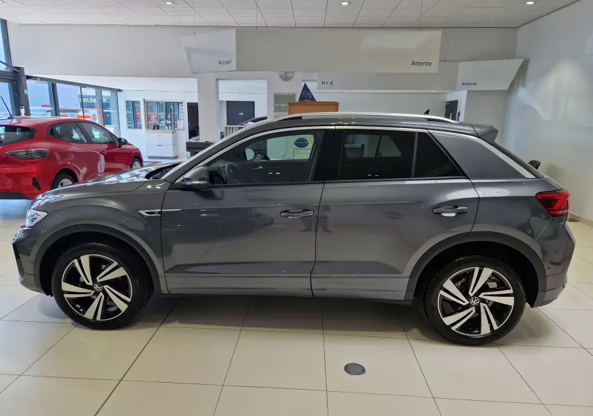 Profil côté gauche d'un Volkswagen T-Roc gris Indium Metal 2025 en finition R-Line Edition avec jantes alliage bicolores.