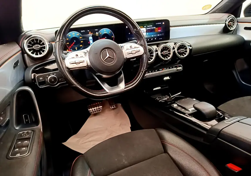 Intérieur noir de la Mercedes CLA 200 d AMG Line 2021, vue cockpit avec volant cuir, écran tactile et aérateurs ronds chromés.