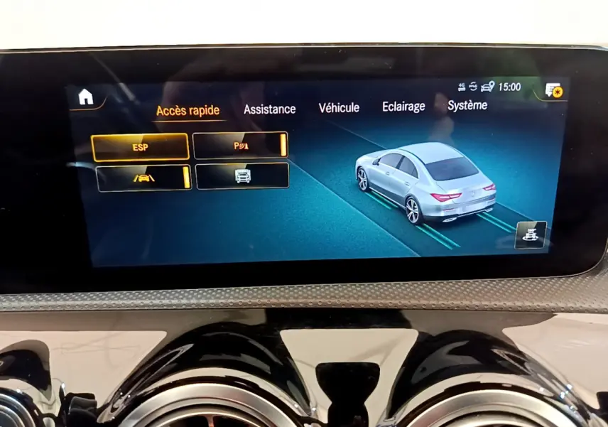 Écran tactile intérieur montrant l'assistance au stationnement avec une voiture grise vue de trois quarts arrière.