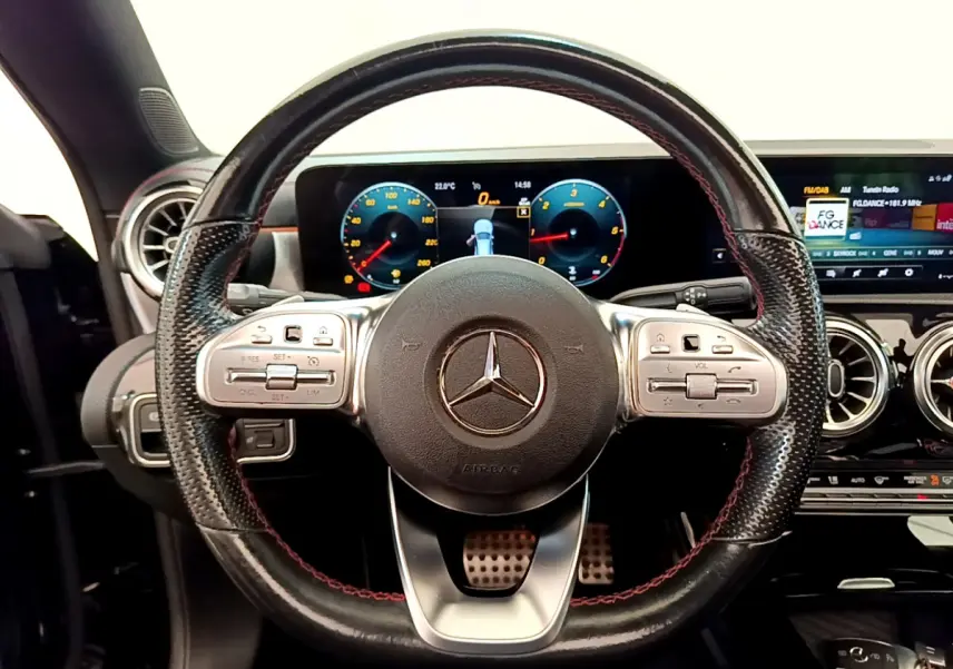 Vue intérieure centrée sur le volant cuir noir avec surpiqûres rouges de la Mercedes CLA 200 d AMG Line 2021.