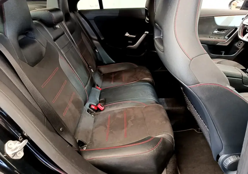 Vue intérieure côté gauche des sièges arrière noirs avec surpiqûres rouges de la Mercedes CLA 200 d AMG Line 2021.