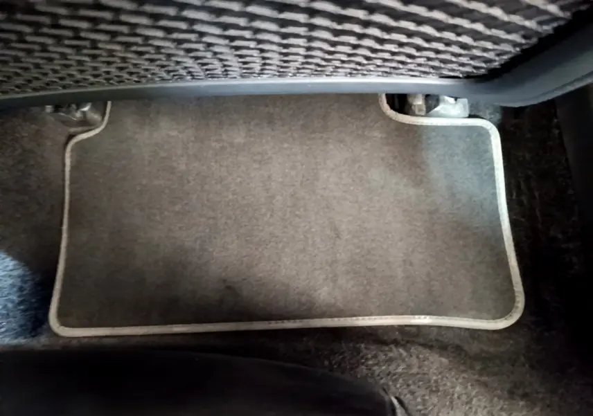 Tapis de sol gris clair sous le siège arrière d'une Mercedes CLA 200 d AMG Line noir, vue rapprochée intérieure.