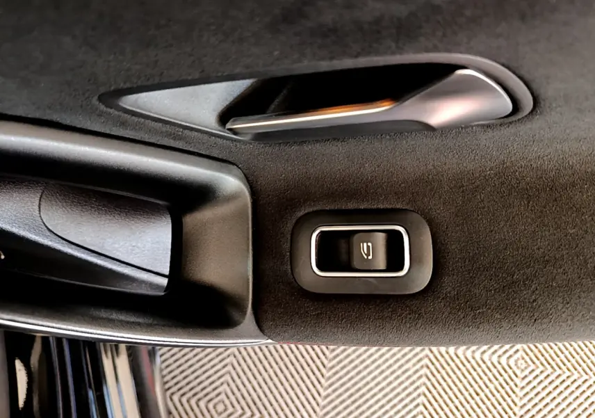 Gros plan sur la poignée intérieure et le bouton de verrouillage de la porte côté gauche d'une Mercedes CLA 200 d AMG Line noire.