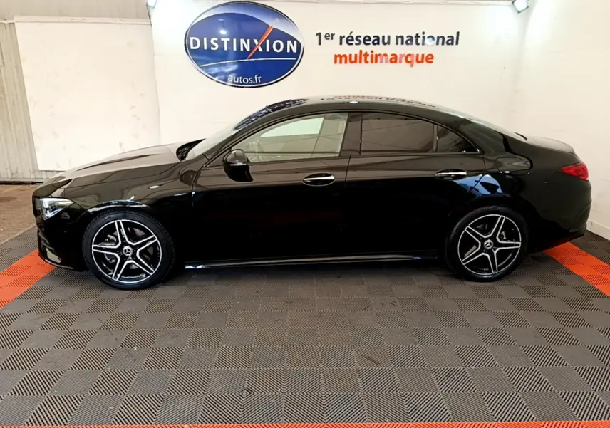 Profil côté gauche d'une Mercedes CLA 200 d AMG Line noire, avec jantes alliage et vitres teintées, en intérieur showroom.