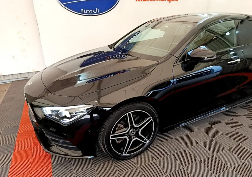 Vue 3/4 avant droit d'une Mercedes CLA 200 d AMG Line noire avec jantes alliage et phares LED allumés.
