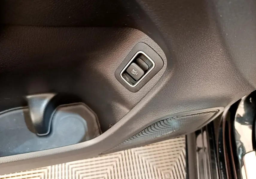 Gros plan sur le bouton de déverrouillage de coffre dans l'habitacle noir de la Mercedes CLA 200 d AMG Line 2021.