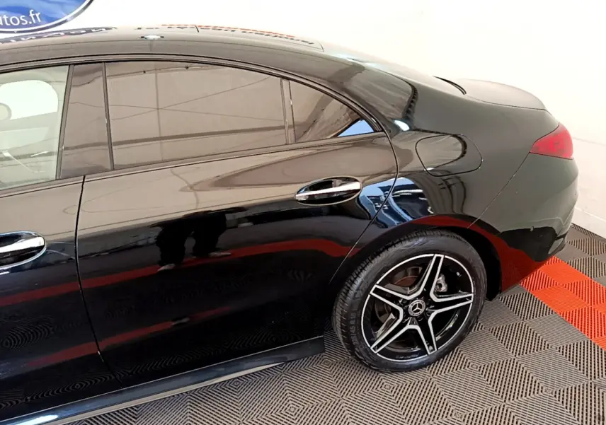 Vue latérale côté droit d'une Mercedes CLA 200 d AMG Line noire mettant en valeur la jante étoile AMG et les vitres teintées.