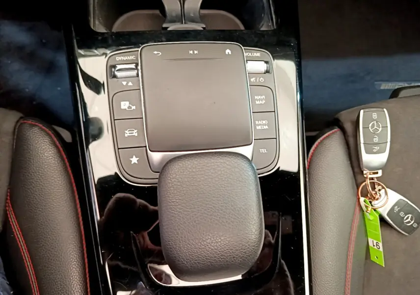Gros plan sur la console centrale noire brillante de la Mercedes CLA 200 d AMG Line avec pavé tactile et clé Mercedes posée à côté
