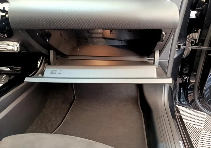 Gros plan sur la boîte à gants ouverte côté passager d'une Mercedes CLA 200 d AMG Line noire.