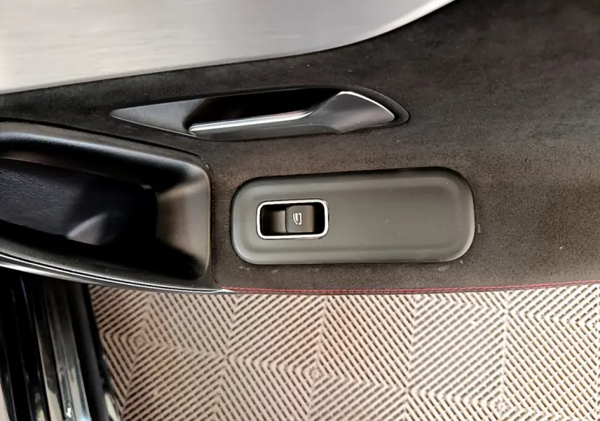 Bouton de commande de lève-vitre côté gauche sur la porte intérieure noire avec surpiqûres rouges d'une Mercedes CLA 200 d AMG Line 2021.