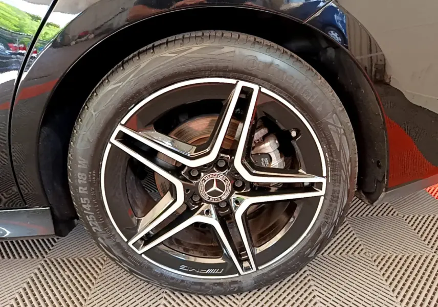 Gros plan sur la roue arrière droite noire d'une Mercedes CLA 200 d AMG Line 2021 avec jante AMG à cinq branches.