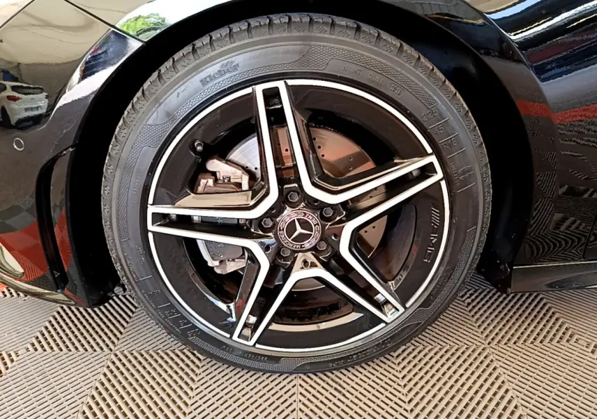 Gros plan sur la roue avant gauche noire d'une Mercedes CLA 200 d AMG Line avec jante étoile bicolore.