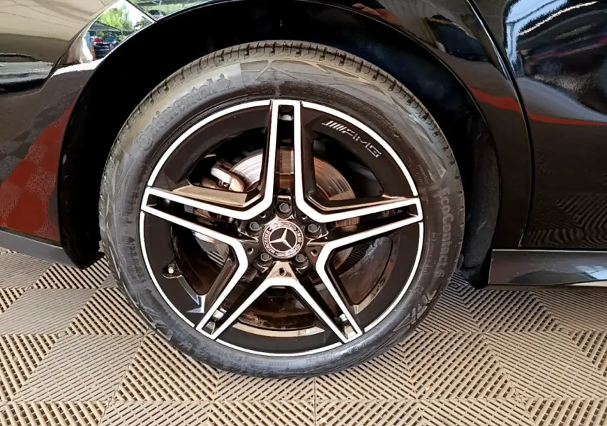 Gros plan sur la roue arrière droite noire d'une Mercedes CLA 200 d AMG Line avec jante AMG étoile cinq branches.