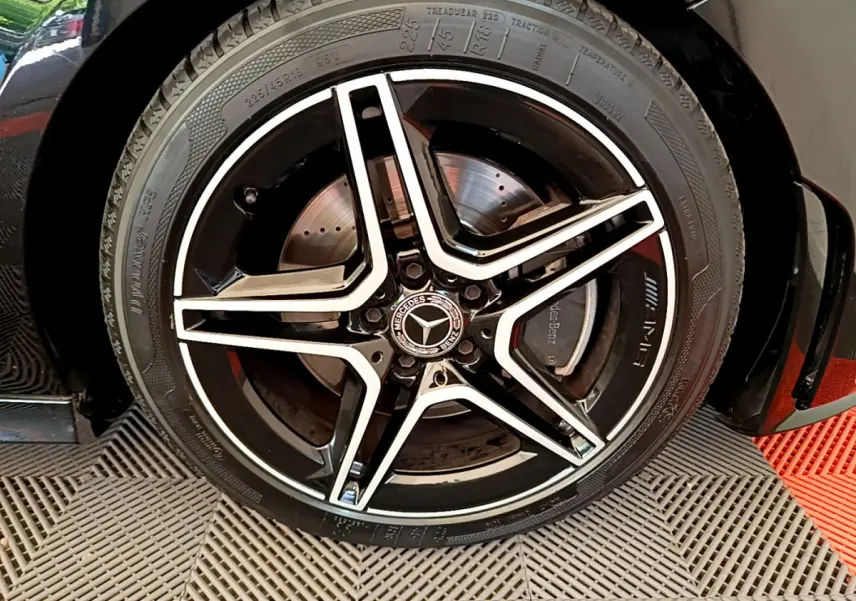 Gros plan sur la jante noire et argentée AMG à cinq branches du côté gauche d'une Mercedes CLA 200 d AMG Line noire de 2021.