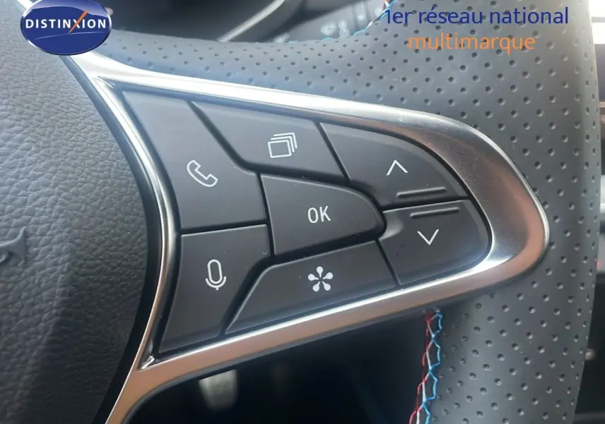 Gros plan sur les commandes multifonctions du volant perforé du Renault Captur E-Tech hybride 2025, finition Esprit Alpine.