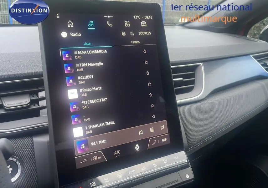 Vue intérieure centrée sur l’écran tactile vertical du tableau de bord du Renault Captur E-Tech rouge passion avec toit noir.