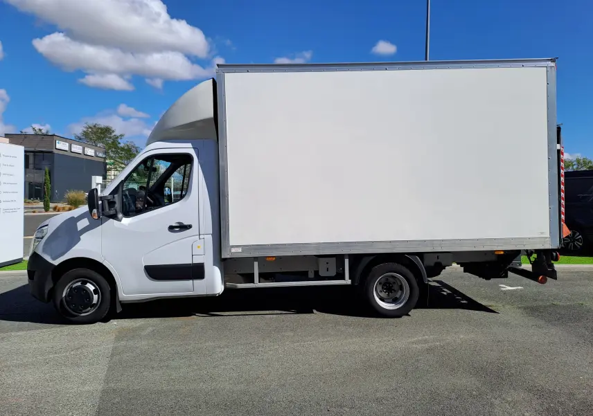 Vue de profil côté gauche d’un Nissan Interstar châssis cabine blanc 2024 avec caisse de livraison sur fond urbain.