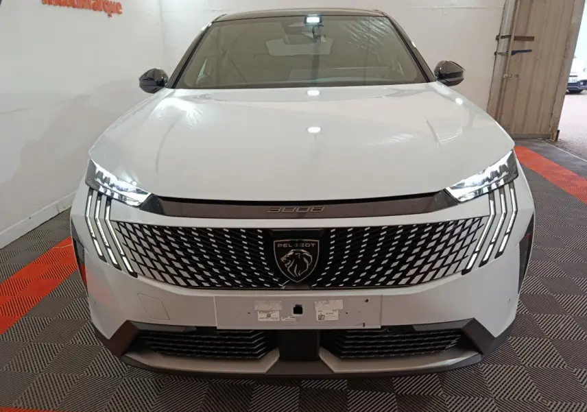 Vue frontale du Peugeot 3008 blanc 2025 avec calandre distinctive et feux LED en griffes allumés.
