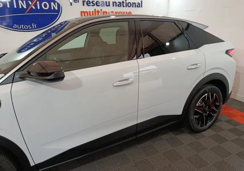 Profil côté gauche du Peugeot 3008 blanc hybride 2025 avec vitres teintées et jantes noires en intérieur showroom.