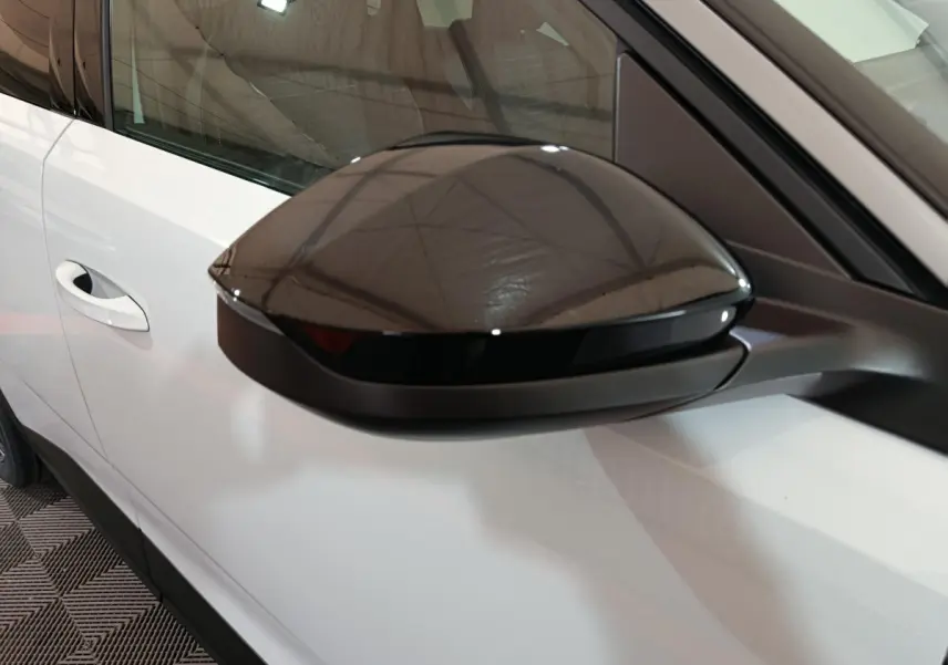 Rétroviseur noir côté gauche sur Peugeot 3008 blanc, vue rapprochée mettant en valeur le contraste des couleurs.