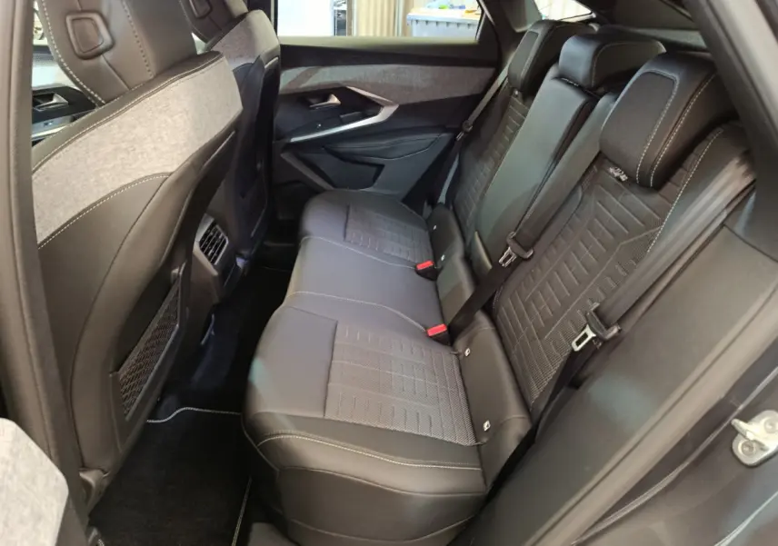 Vue côté droit de la banquette arrière noire et grise du Peugeot 3008 Hybrid 2025 avec finitions soignées et ceintures visibles.