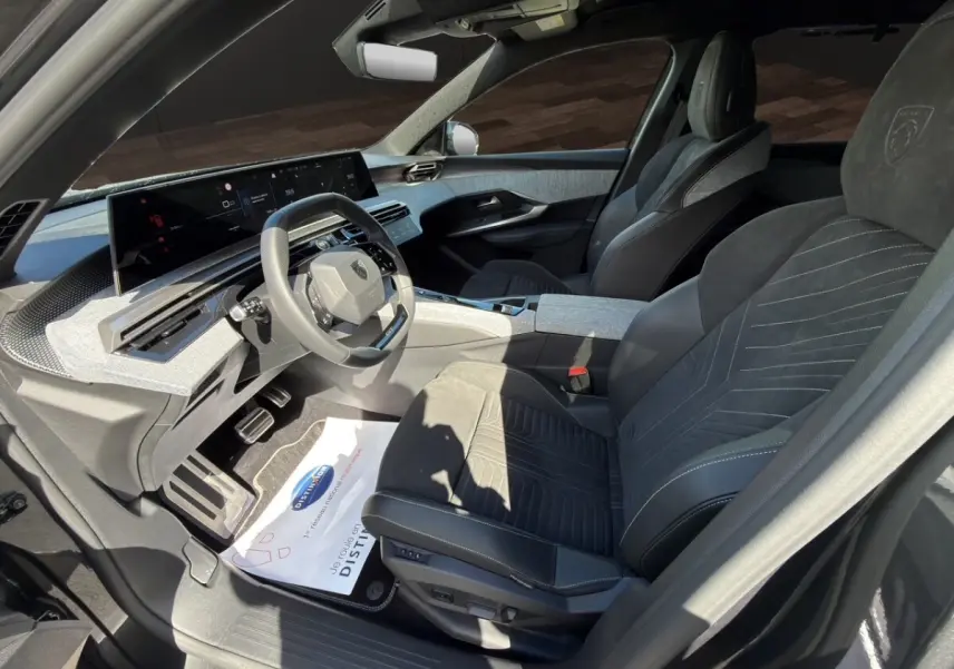 Vue intérieure côté conducteur du Peugeot 5008 gris foncé, avec sièges Alcantara et tableau de bord numérique panoramique.