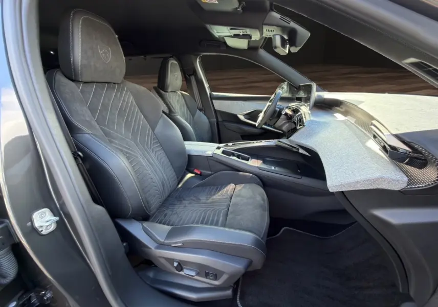 Vue intérieure côté conducteur du Peugeot 5008 gris foncé 2025, sièges Alcantara noirs avec logo Peugeot brodé.