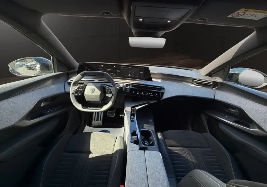 Vue intérieure avant du Peugeot 5008 gris foncé, avec volant compact et tableau de bord numérique large.