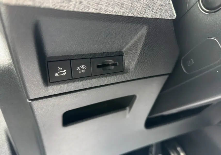 Gros plan sur les commandes de coffre électrique et désactivation de l'assistance, intérieur noir du Peugeot 5008 gris foncé.