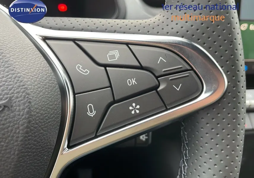 Gros plan sur les commandes multifonctions à droite du volant perforé du Renault Captur E-Tech blanc nacré 2025.