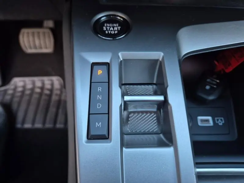 Vue rapprochée de la console centrale grise avec commandes de boîte auto et bouton start/stop dans une Peugeot 308 Vert Olivine