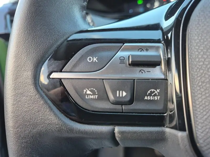 Gros plan sur les commandes au volant côté gauche du Peugeot 308 2023, boutons de limitation et assistance de vitesse.