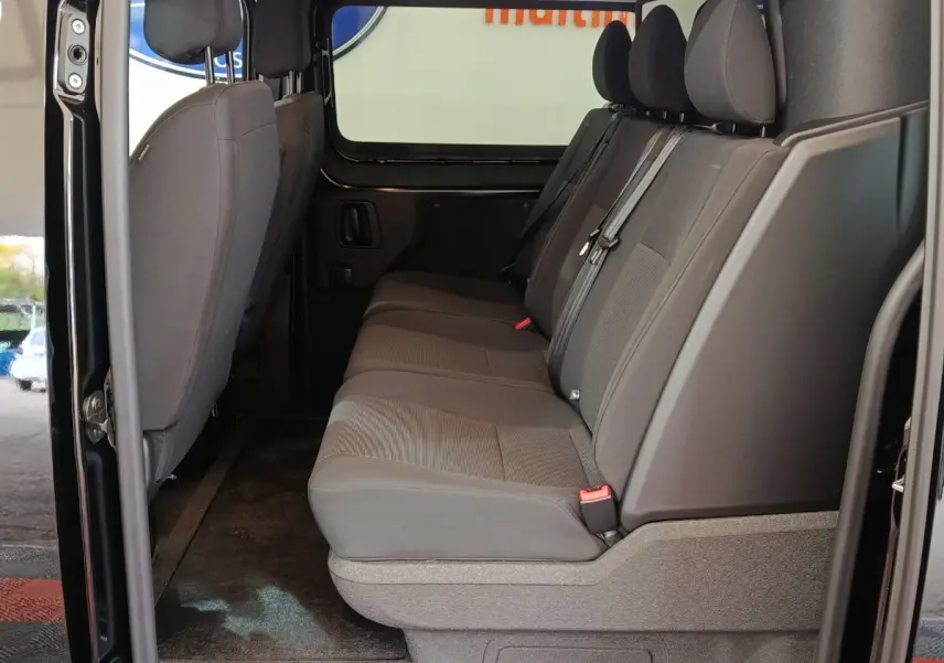 Vue latérale intérieure sur la banquette arrière grise du Citroën Jumpy XL noir avec portes ouvertes.