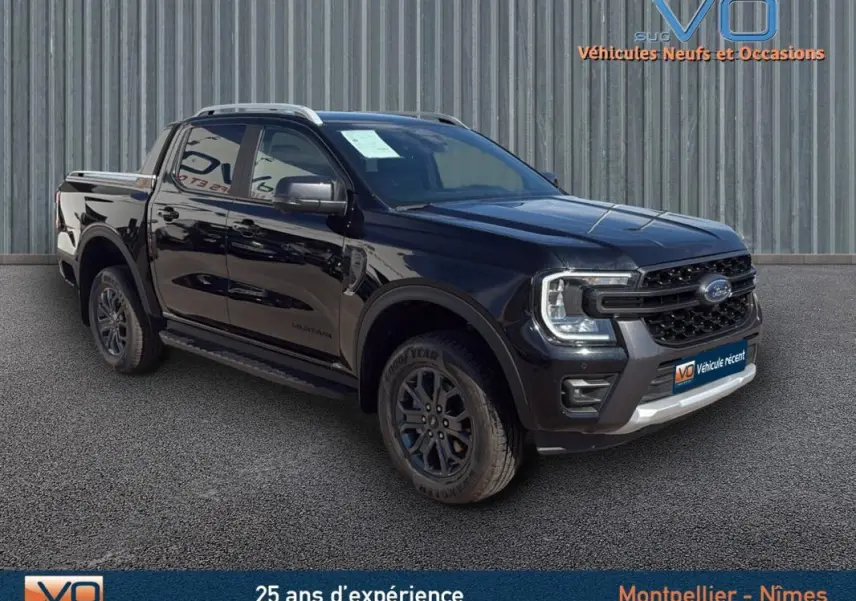 Ford Ranger Wildtrak noir en 3/4 avant droit, avec barres de toit, marchepieds et jantes alliage 18 pouces.