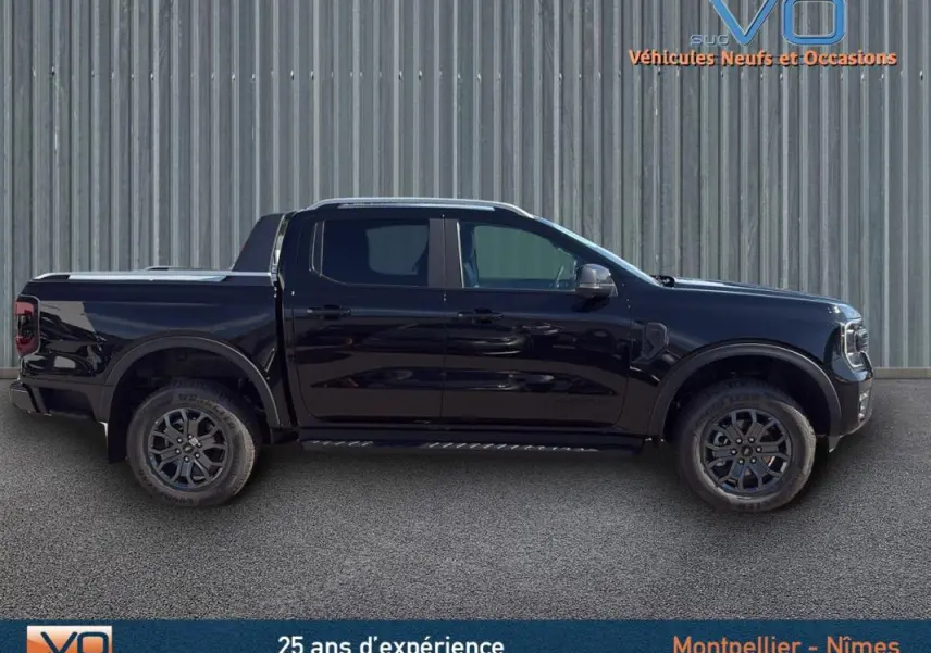 Vue de profil côté gauche du Ford Ranger Wildtrak noir avec barres de toit et jantes alliage 18 pouces.