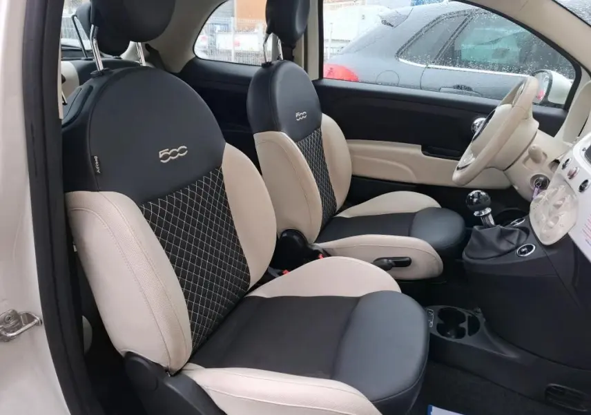 Vue intérieure côté conducteur de la FIAT 500 Dolcevita 2022 avec sièges bicolores beige et noir et volant beige.